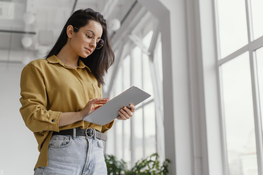 Mujer de pie sosteniendo una tablet mientras lee.